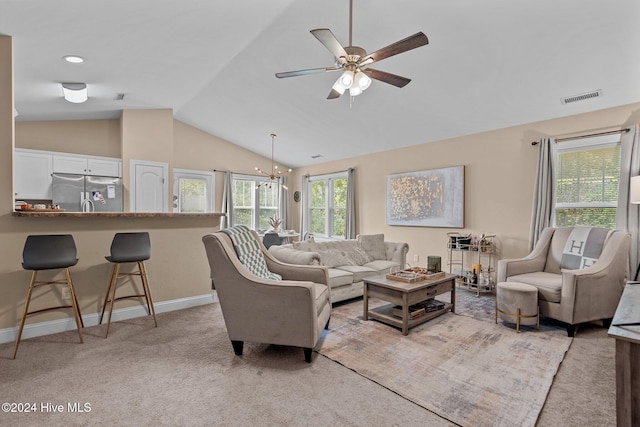 living room featuring ceiling fan with notable chandelier, light colored carpet, and vaulted ceiling