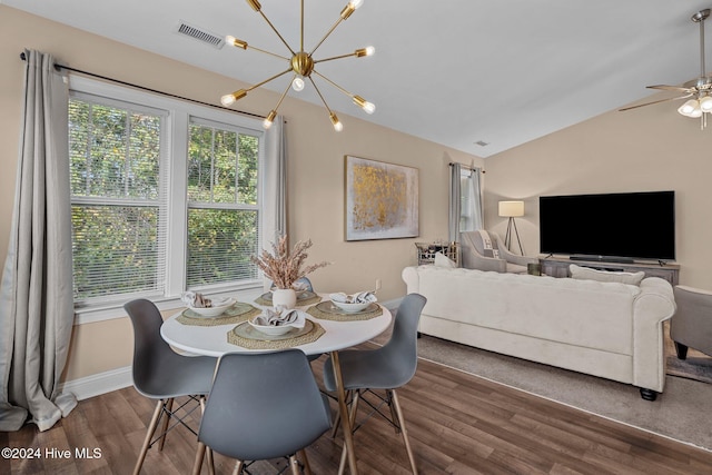 dining space featuring dark hardwood / wood-style floors, ceiling fan with notable chandelier, and vaulted ceiling