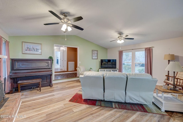 living room with ceiling fan, light hardwood / wood-style floors, and vaulted ceiling