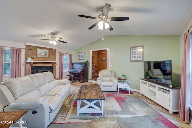 living room featuring ceiling fan, light hardwood / wood-style floors, vaulted ceiling, and a brick fireplace