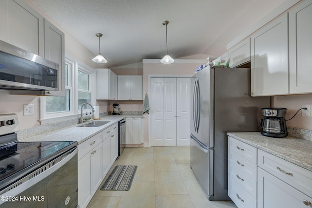 kitchen with white cabinetry, sink, pendant lighting, appliances with stainless steel finishes, and lofted ceiling