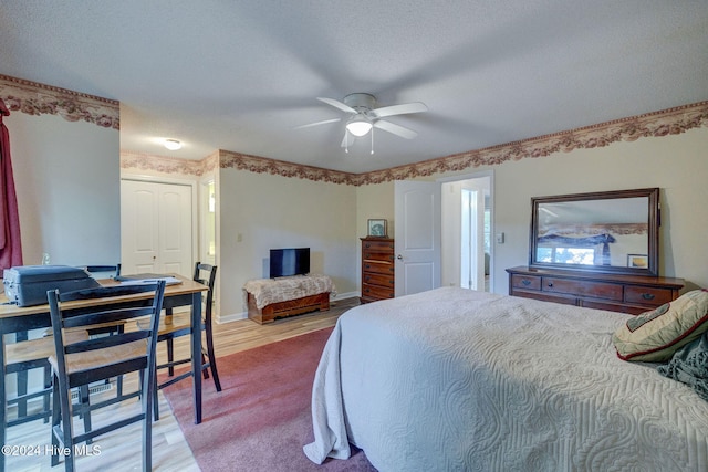 bedroom featuring ceiling fan, a closet, a textured ceiling, and light wood-type flooring