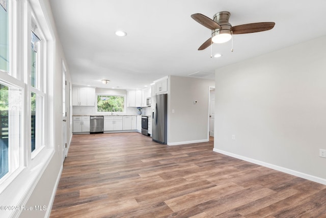 unfurnished living room featuring hardwood / wood-style flooring, ceiling fan, and sink