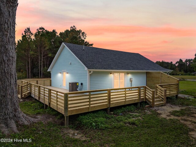 back house at dusk with a deck and cooling unit