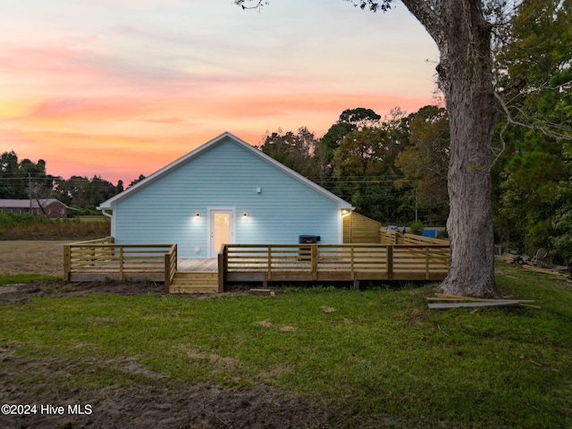 back house at dusk with a yard and a wooden deck