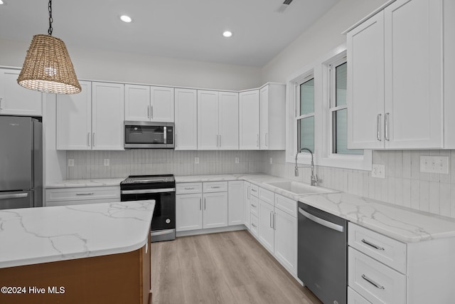 kitchen featuring white cabinetry, sink, stainless steel appliances, light stone counters, and pendant lighting