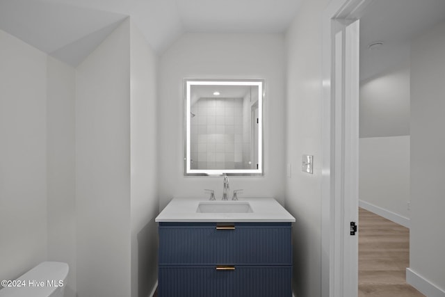 bathroom with vanity, hardwood / wood-style flooring, toilet, and lofted ceiling