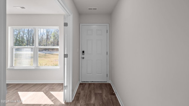 entryway with baseboards, wood finished floors, visible vents, and a healthy amount of sunlight