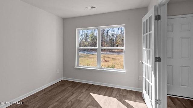 interior space with dark wood-style floors, a wealth of natural light, visible vents, and baseboards