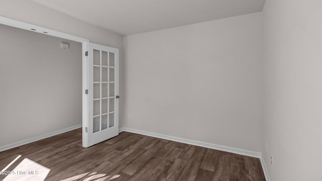 empty room featuring dark wood-type flooring and baseboards