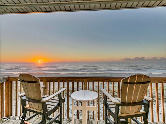 deck at dusk with a beach view and a water view