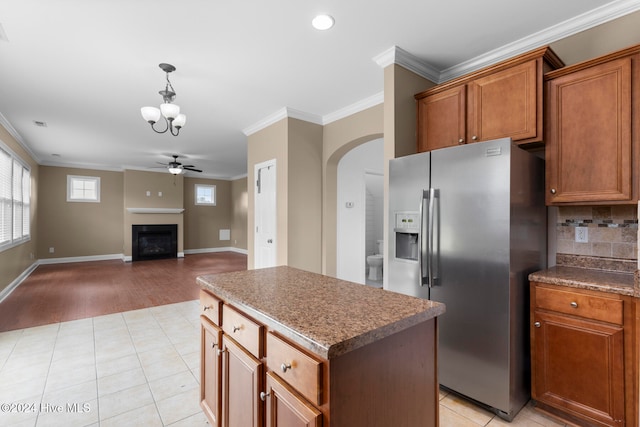 kitchen featuring a kitchen island, ornamental molding, stainless steel fridge, light wood-type flooring, and tasteful backsplash