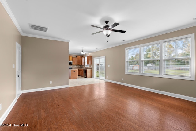 unfurnished living room with ornamental molding, ceiling fan with notable chandelier, and light hardwood / wood-style floors