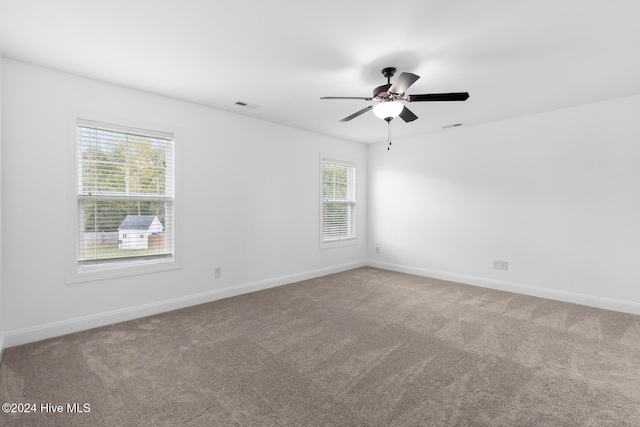 carpeted empty room with a healthy amount of sunlight and ceiling fan