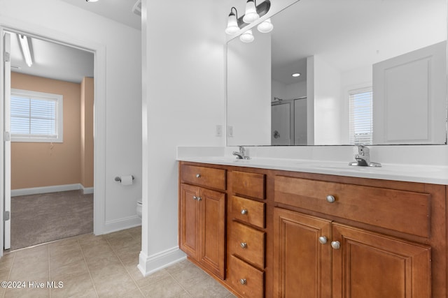 bathroom with a shower with door, vanity, toilet, and tile patterned flooring