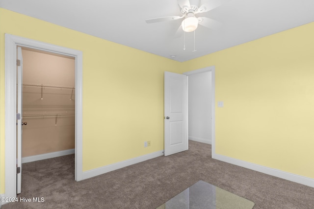 unfurnished bedroom with a closet, ceiling fan, carpet, and a walk in closet