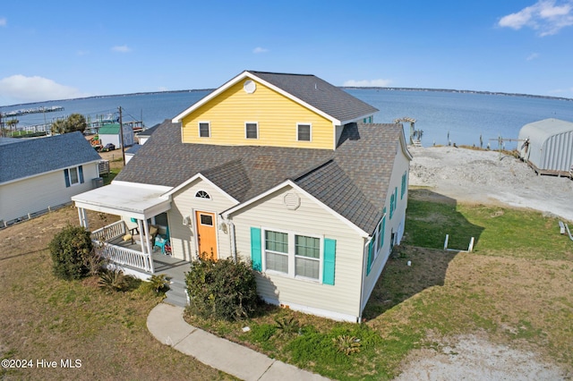 view of front of home with a porch, a front lawn, and a water view