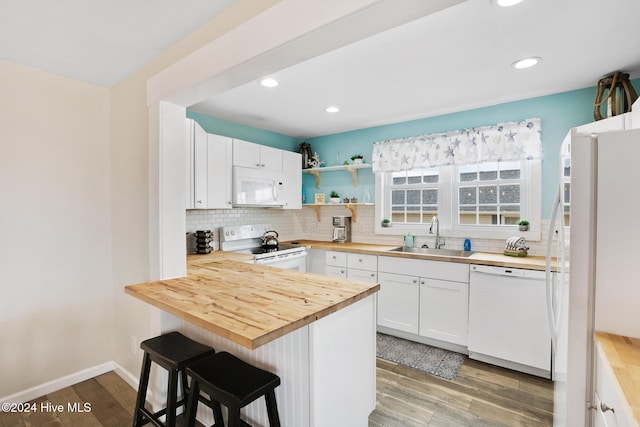 kitchen with white cabinets, light wood-type flooring, wooden counters, sink, and white appliances