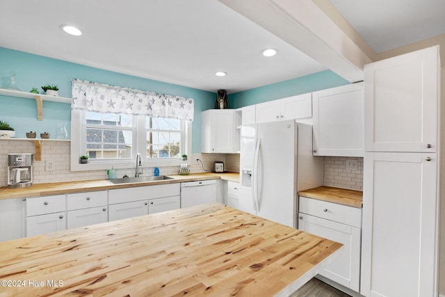 kitchen with white appliances, sink, butcher block counters, white cabinets, and decorative backsplash