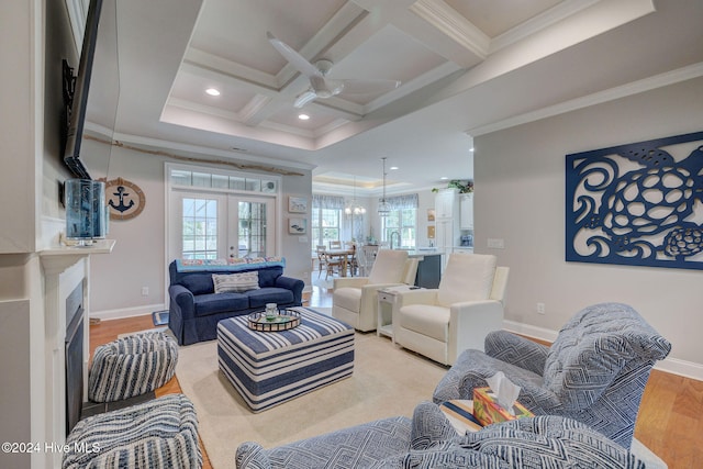 living room featuring coffered ceiling, ornamental molding, ceiling fan, beam ceiling, and light hardwood / wood-style flooring