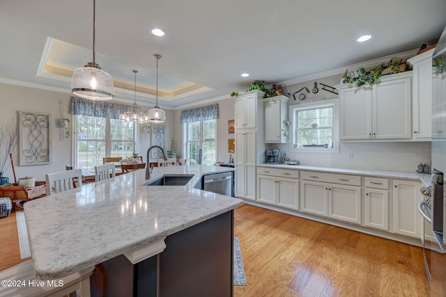 kitchen featuring white cabinets, a large island with sink, hanging light fixtures, and sink