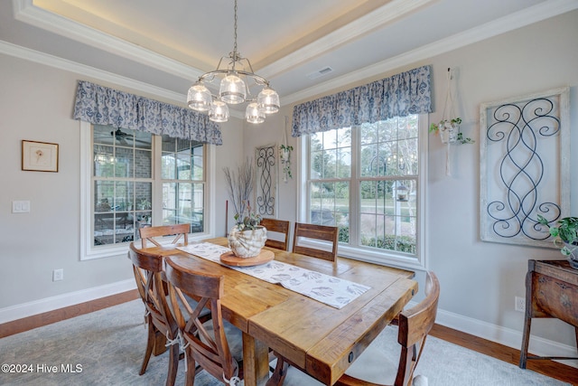 dining room featuring an inviting chandelier, a tray ceiling, hardwood / wood-style floors, and ornamental molding