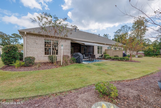 rear view of house with a lawn and a patio