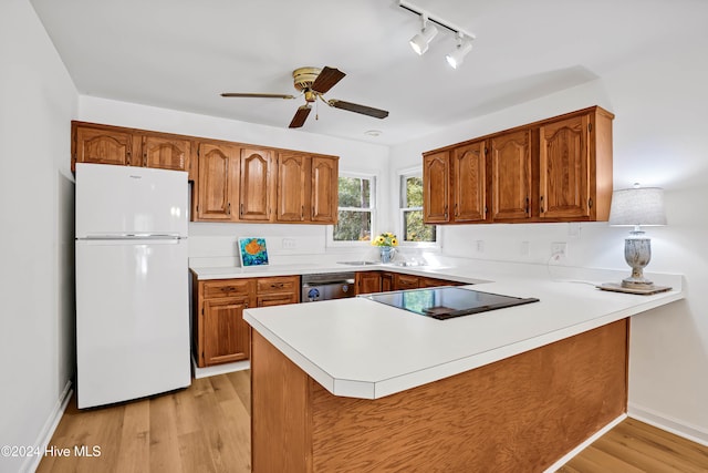 kitchen with light hardwood / wood-style floors, kitchen peninsula, dishwasher, and white refrigerator