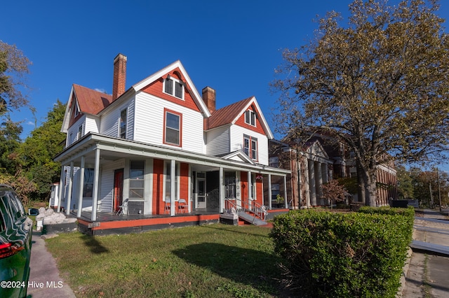 victorian-style house featuring a porch and a front lawn