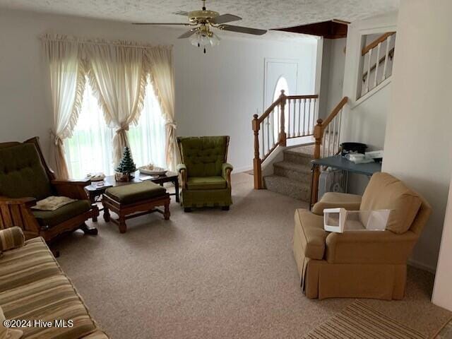 living room featuring a textured ceiling, carpet flooring, and ceiling fan