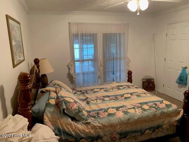 carpeted bedroom with crown molding and ceiling fan