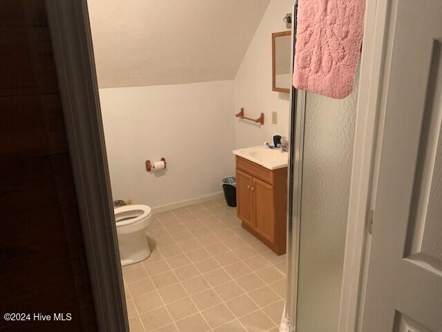 bathroom featuring vanity, toilet, lofted ceiling, and tile patterned flooring