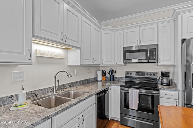 kitchen featuring sink, white cabinets, stainless steel appliances, and ornamental molding