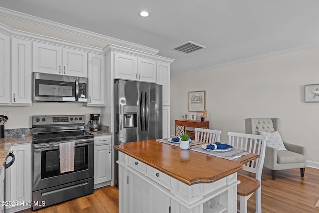 kitchen featuring white cabinetry, ornamental molding, light wood-type flooring, and appliances with stainless steel finishes