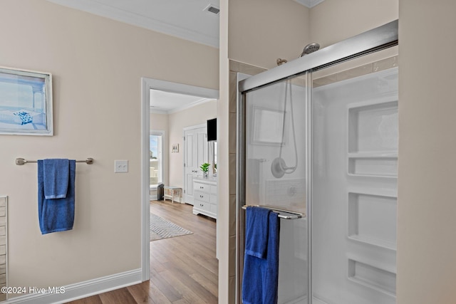 bathroom featuring hardwood / wood-style floors, ornamental molding, and walk in shower