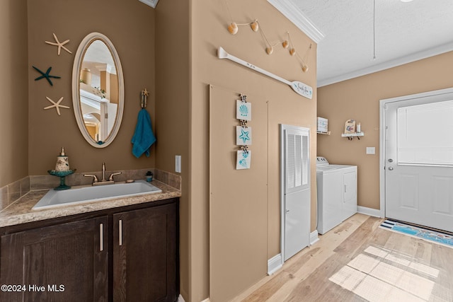 bathroom featuring a textured ceiling, hardwood / wood-style flooring, washing machine and dryer, vanity, and crown molding