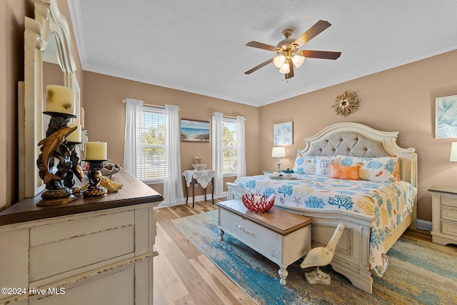 bedroom with crown molding, a textured ceiling, light hardwood / wood-style floors, and ceiling fan