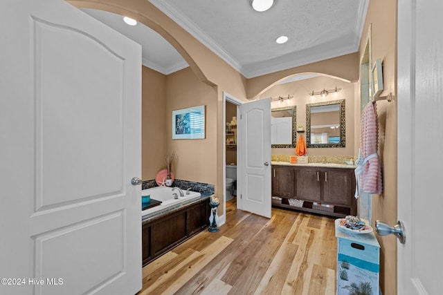 bathroom featuring toilet, a tub, hardwood / wood-style floors, crown molding, and vanity