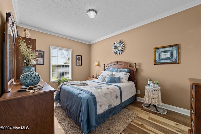 bedroom with crown molding, a textured ceiling, and light wood-type flooring