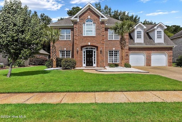 1109 Foxbow Cv, Leland, NC 28451 - georgian-style home featuring driveway, brick siding, a front yard, and a shingled roof