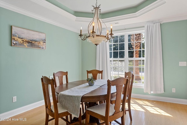 1109 Foxbow Cv, Leland, NC 28451 - dining area featuring a chandelier, light wood-type flooring, baseboards, a tray ceiling, and crown molding