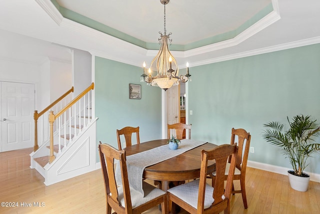 1109 Foxbow Cv, Leland, NC 28451 - dining area with light wood-style flooring, a chandelier, a tray ceiling, crown molding, and stairs