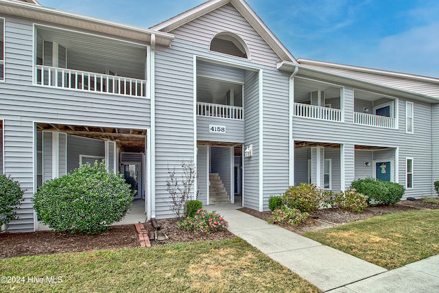 townhome / multi-family property featuring a balcony and a front lawn