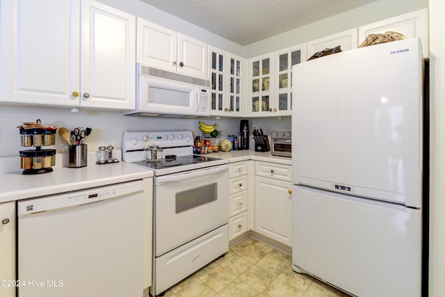 kitchen with white cabinets, a textured ceiling, and white appliances