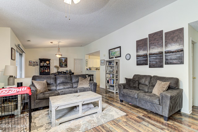 living room featuring dark wood-type flooring, vaulted ceiling, and a textured ceiling