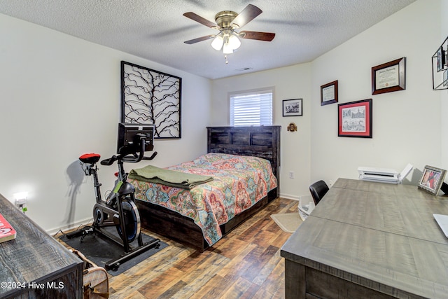 bedroom with ceiling fan, wood-type flooring, and a textured ceiling