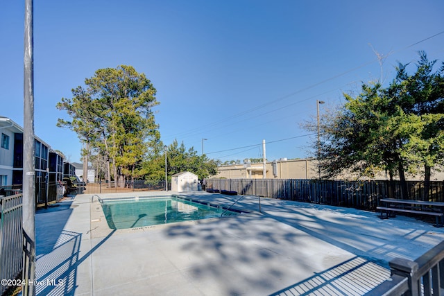 view of swimming pool with a patio and a storage unit