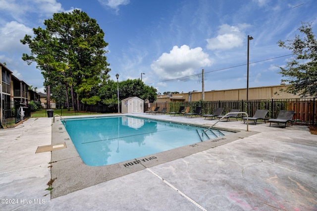 view of swimming pool with a patio and a storage unit