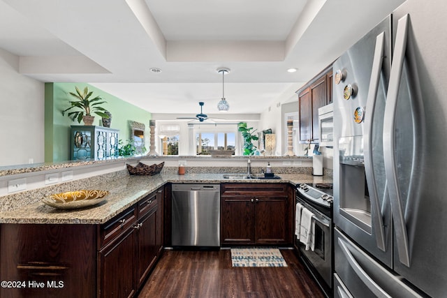 kitchen featuring sink, stainless steel appliances, light stone counters, dark hardwood / wood-style flooring, and kitchen peninsula