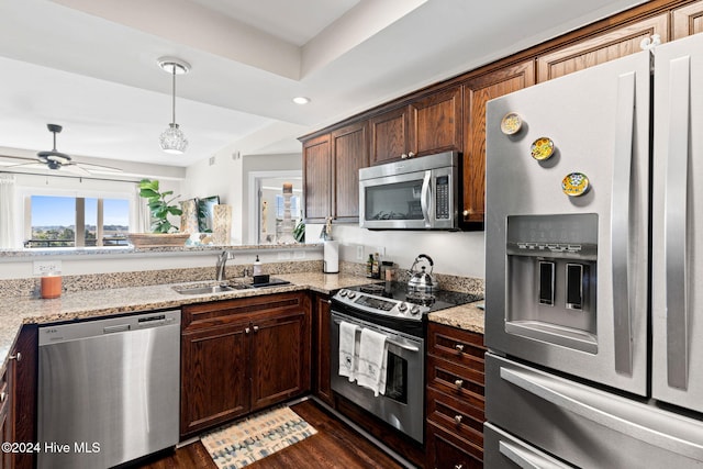 kitchen with light stone counters, sink, dark wood-type flooring, and appliances with stainless steel finishes